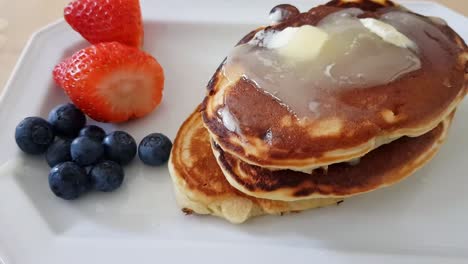 Pancakes-with-honey-butter-topping-and-fruit-on-the-side
