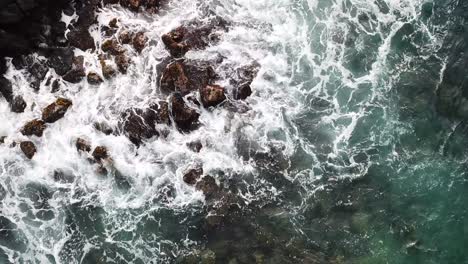 Steady-above-shot-of-waves-hitting-rocks-in-ocean