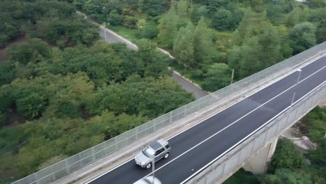Drone-shot-of-a-Land-Rover-on-a-road-surrounded-by-trees