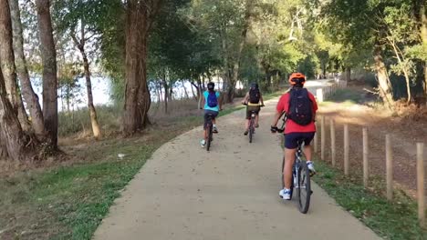 1-Hombre-Y-2-Mujeres-En-Bicicleta-En-Un-Día-Soleado-Cerca-Del-Río