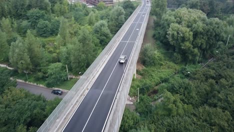 Drone-shot-of-a-Land-Rover-on-a-road-surrounded-by-trees