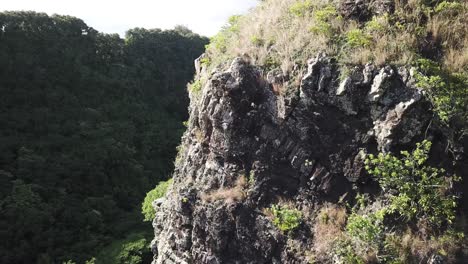 Drohnenschwenk-Nach-Links,-Um-Wasserfall-Hinter-Klippe-In-Kauai,-Regenwald-Von-Hawaii,-Am-Tag-Zu-Enthüllen