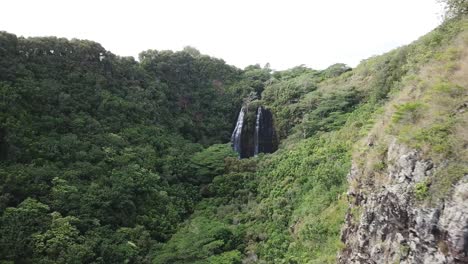 Drone-flying-towards-waterfall-in-Kauai,-Hawaii-in-lush-rainforest