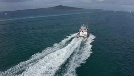 Fishing-boat-sailing-fast-on-open-sea-near-Mission-Bay,-Auckland,-aerial-shot
