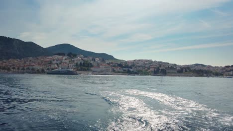 Vista-De-Una-Hermosa-Ciudad-De-Hvar-Desde-Un-Bote,-Dejando-Un-Rastro-De-Olas-Detrás-De-él