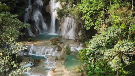 Hidden-Exotic-Paradise,-Waterfall-and-Natural-Turquoise-Pools-in-Laos,-Kuang-Si-Falls-Approaching-Aerial
