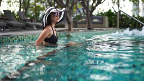 Asiatische-Frau-In-Einem-Resort-Swimmingpool-Lächelt-Und-Schaut-In-Die-Kamera