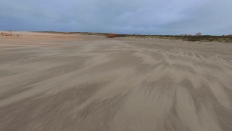 Drone-flying-fast-and-low-at-the-beach,-during-a-cold-windy-day-in-the-Netherlands