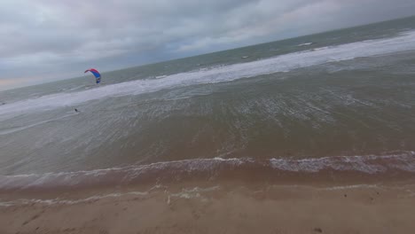 Wide-aerial-orbit-shot-of-a-Dutch-beach-with-a-kitesurfer