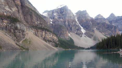 landscape-view-at-moraine-lake-with-people-canoeing-on-green-mirror-lake-surface-and-rockies-mountain-range-in-summer-daytime