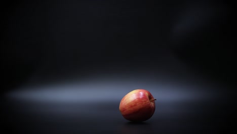Slow-Motion-View-of-a-Ripe-Red-Apple-Spinning-on-a-Black-Surface