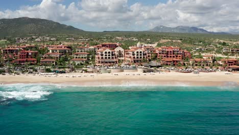 Aerial,-tracking,-drone-shot,-of-hotels-at-the-Sheraton-beach,-on-a-sunny-day,-in-Cabo-San-Lucas,-Baja-California-sur,-in-Mexico