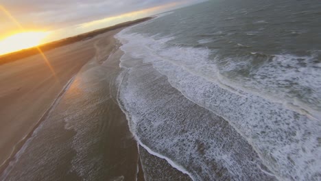 Aerial-shot-of-a-kitesurfer-jumping-over-a-sandbank-during-sunset
