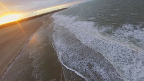 Toma-Aérea-De-Un-Kitesurfer-Saltando-Sobre-Un-Banco-De-Arena-Durante-La-Puesta-De-Sol