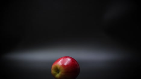 Close-up-of-a-Ripe-Red-Apple-Spinning-on-a-Black-Surface,-Slow-Motion