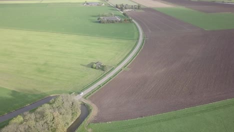 drone-shot-of-the-road-surrounded-by-the-farm-fields-in-the-Netherlands
