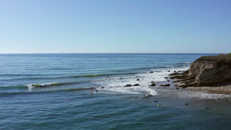 Aerial,-Distant-surfers-in-gentle-ocean-waves-of-California-coast