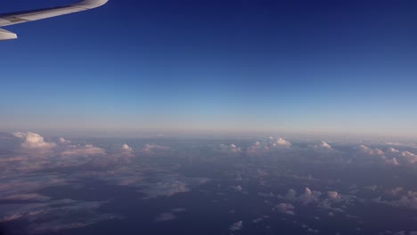 Clear-blue-sky-on-the-horizon-and-small-white-clouds-seen-from-a-plane-up-in-the-sky