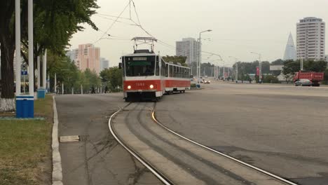Vintage-Electric-Tram-Approaches-Tram-Stop-In-Downtown-Pyongyang,-North-Korea