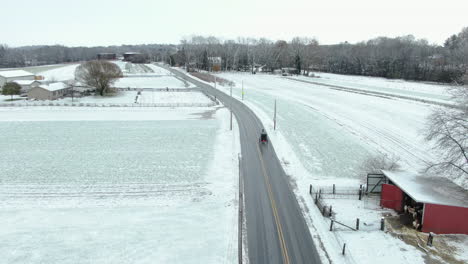 Pennsylvania-Landschaft-Bedeckt-Mit-Einer-Dünnen-Schicht-Des-Ersten-Saisonalen-Schnees,-Eine-Pferdekutsche-Auf-Einer-Leeren-Straße,-Die-An-Einem-Holzschuppen-In-Leuchtend-Roter-Farbe-Vorbeiführt