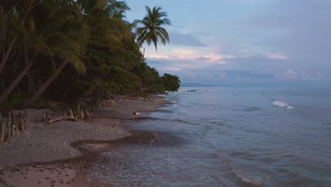 Epische-Luftaufnahme-Eines-Natürlichen-Dschungelwaldes-Und-Eines-Sandstrandes-An-Der-Pazifikküste-In-Costa-Rica-Bei-Sonnenuntergang-Mit-Einem-Wunderschönen-Farbigen-Himmel-Und-Wolken-über-Dem-Meer