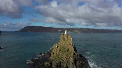 Distinctive-Ninepin-Rock-with-lighthouse-beacon-on-top,-Huia-Reserve,-New-Zealand