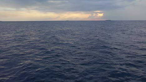Luftaufnahme,-Drohnenaufnahme,-Niedrig-Nahe-Der-Oberfläche,-über-Einem-Dunklen,-Phantomblauen-Meer,-Auf-Dem-Indischen-Ozean,-An-Einem-Teilweise-Sonnigen-Abend,-Auf-Den-Malediven-Inseln
