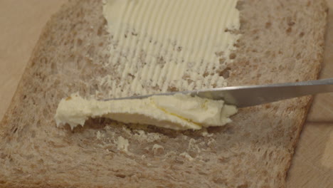 Margarine-butter-being-spread-on-slice-of-whole-grain-bread