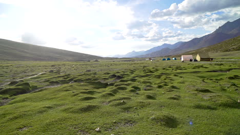 Handheld-shot-as-walking-around-a-tent-camp,-Nimaling-in-the-Himalayas-on-an-open-green-field