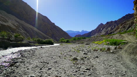 Pan-right-low-angle-shot-in-a-river-bed,-dry-season-and-the-river-have-shrunk-revealing-the-stony-bottom
