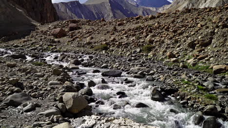 Tilt-up-shot-on-the-Markha-Valley-trek-as-a-river-flowing-at-the-bottom-of-the-Kongmaru-La-mountain-with-snowy-peak