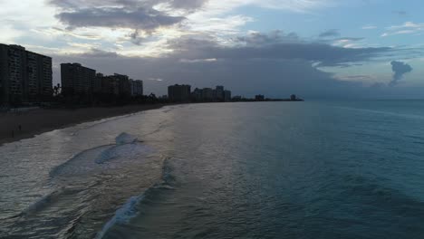 Droning-along-Isla-Verde-beaches-as-the-sun-sets-behind-the-clouds