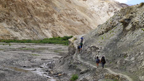 A-group-of-tourists-hiking-in-the-Markha-Valley-on-a-dirt-road-with-backpacks