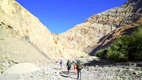 Tilt-down-to-a-group-of-hikers,-backpacker-tourists-on-the-Markha-Valley-trek-on-a-sunny-day