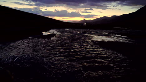 Nach-Oben-Geneigte-Dunkle-Aufnahme-Von-Einem-Fluss-Zu-Einer-Sonnenuntergangsszene-über-Einer-Bergkette-Im-Himalaya