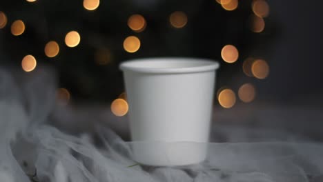 Handheld-shot-of-a-christmas-paper-cup-with-bokeh-fairy-lights