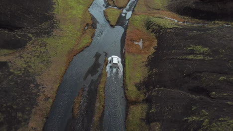 SUV-Crossover-Vehicle-in-Shallow-River-Moving-Further-on-Muddy-Road-in-Amazing-Landscape-of-Iceland