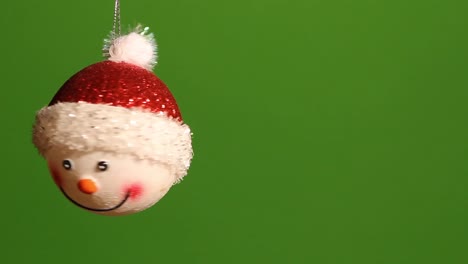 Snowman-ornament-spins-on-a-silver-cord-in-front-of-a-green-screen