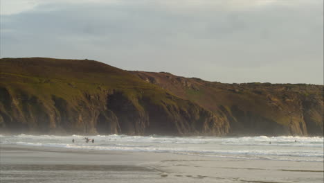 Perranporth-sands-beach,-Cornwall,-England-with-waves-breaking-fast-on-shore,-panning-shot