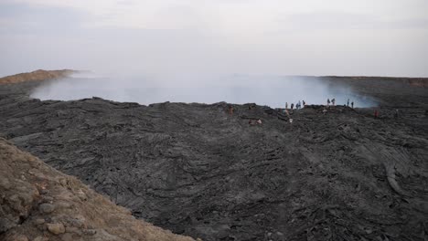 Wide-shot,-view-of-people-walking-along-the-smoky-crater-of-Dallol-volcano-in-Ethiopia