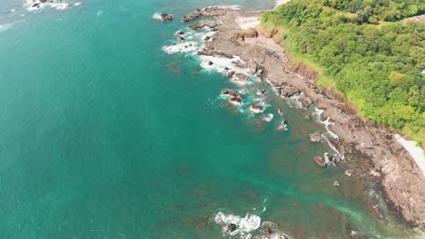 Beautiful-4K-aerial-drone-shot-of-a-tropical-Pacific-paradise-beach-at-the-seaside-coast-in-Costa-Rica-with-waves,-jungle,-rocks-and-sand