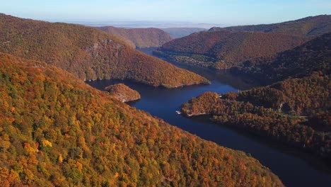 Panoramic-aerial-shot-of-lake-Tarnita,-Romania,-surrounded-by-colorful-autumn-trees