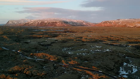 Drone-aerial-shot-on-typical-Iceland-landscape,-with-red-sand,-mountains-and-snow