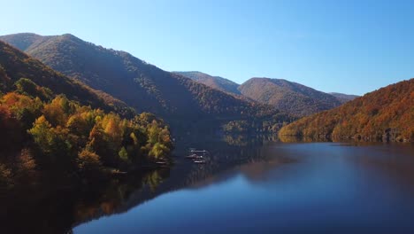 Drohnenblick-Nach-Vorne-über-Den-Tarnita-See,-Rumänien,-Umgeben-Von-Bunten-Herbstbäumen