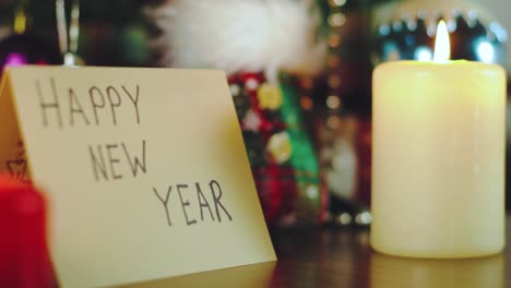 Greeting-card-saying-"Happy-New-Year"-with-candles-and-Christmas-tree-and-decorations-around-it