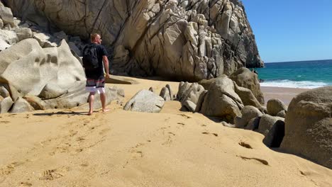 Tourist-man-walking-along-quiet-Cabo-beach,-still-shot