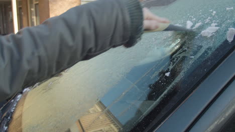 Scratching-ice-from-car-window-on-a-sunny-winter-morning