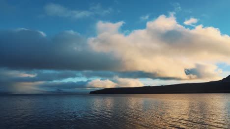 Eine-Schöne-Fahrtaufnahme-Des-Arktischen-Friedlichen-Meer--Und-Berghangs-Unter-Einem-Bewölkten-Blauen-Himmel,-Island,-Westfjorde