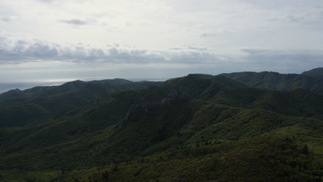 Epic-open-shot-of-a-huge-megalithic-formations-on-top-of-a-forested-mountain-ridge-with-ocean-in-the-far-distance-on-a-cloudy-day