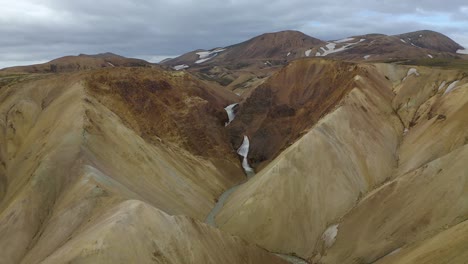 Drohnenvideo-Fliegt-In-Eine-Schlucht-Zu-Einem-Wasserfall-Im-Farbenfrohen-Hochland-Von-Island
